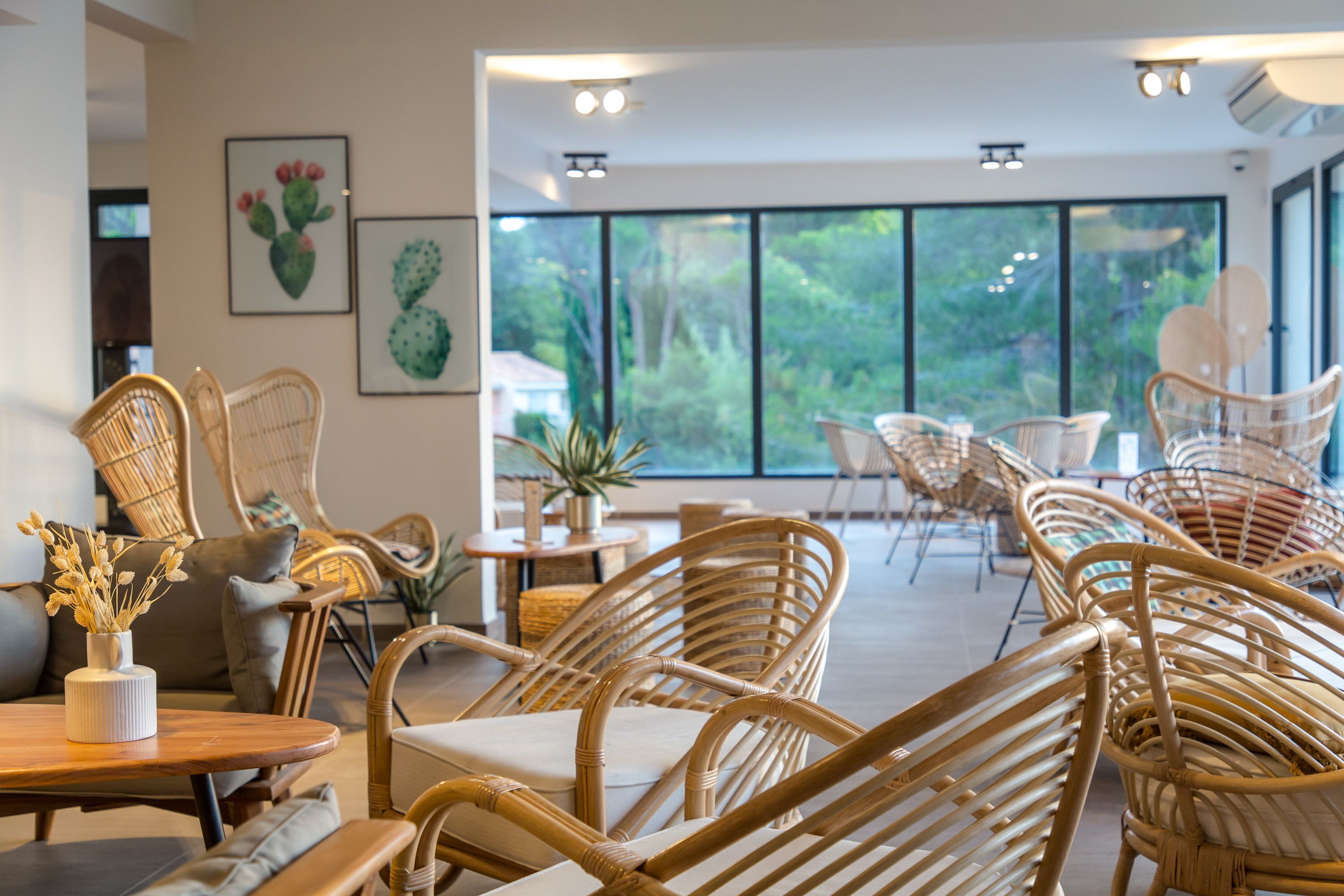 A modern interior with wicker furniture, large windows, and artwork on the walls.