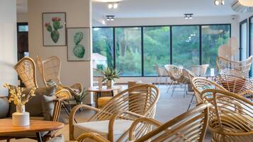 A modern interior with wicker furniture, large windows, and artwork on the walls.