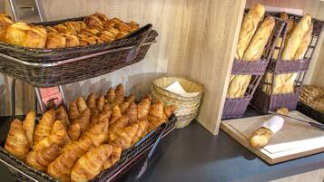 Et udvalg af bagværk, herunder croissanter og baguetter, anrettet i fletkurve på en bordplade.