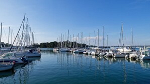 Ein Yachthafen mit mehreren angestaubten Booten, ruhigem Wasser und klarem Himmel.
