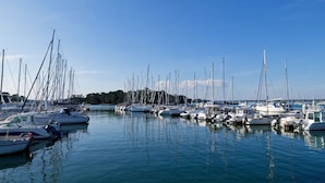 Un port de plaisance où sont amarrés de nombreux bateaux, l’eau est calme et le ciel est dégagé.