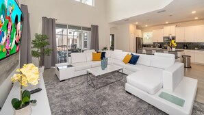 A spacious living room with a sectional sofa, a coffee table, and a TV on the wall. - SG2764 Storey lake  5 bed 5 bath Private Pool & Free Waterpark (Kissimmee)