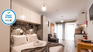 Une chambre d’hôtel propre et sûre, équipée d’un lit, d’une chaise, d’une table et d’un coin cuisine.