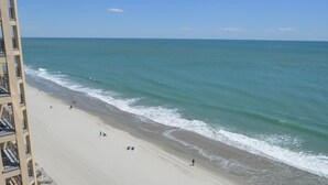 Ein Strand mit einem Hochhaus am Rand.