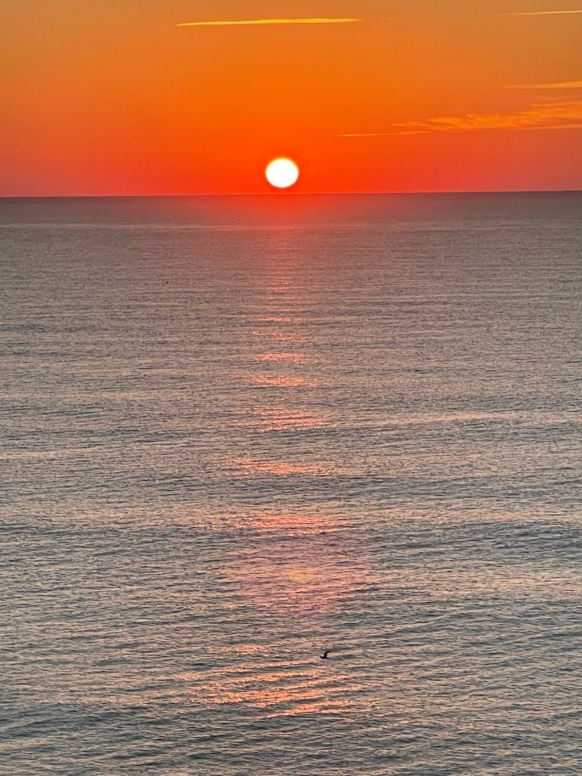 A sunset over a calm sea with a visible horizon.