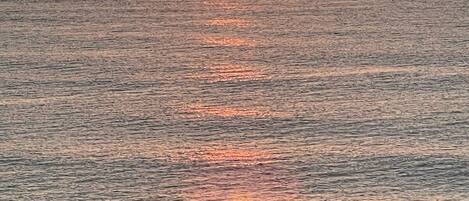 A sunset over a calm sea with a visible horizon.