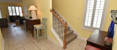 A living room with a staircase, a dining area, and a bookshelf.