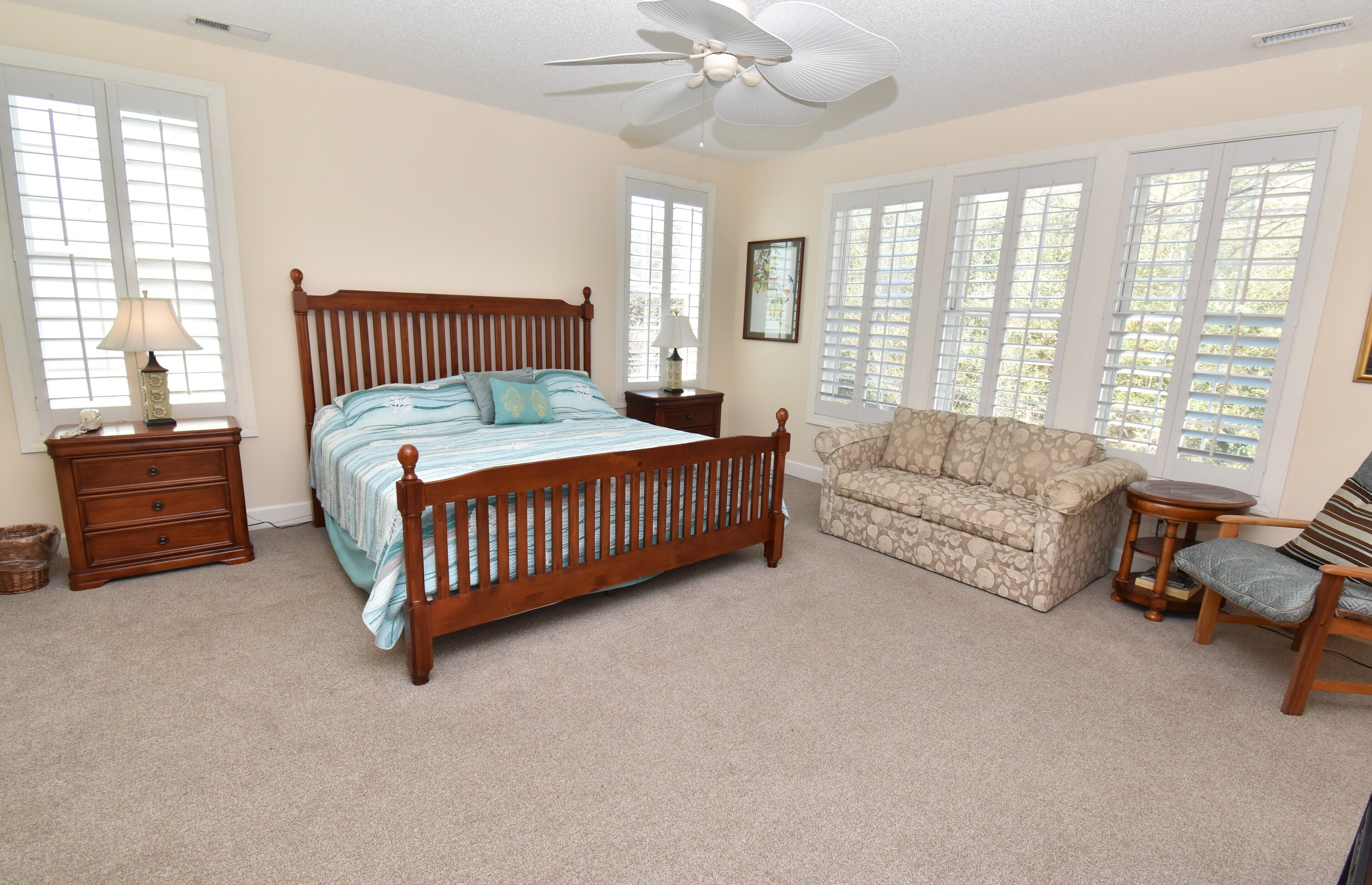 A bedroom with a wooden bed, a nightstand, a dresser, a sofa, and a chair.