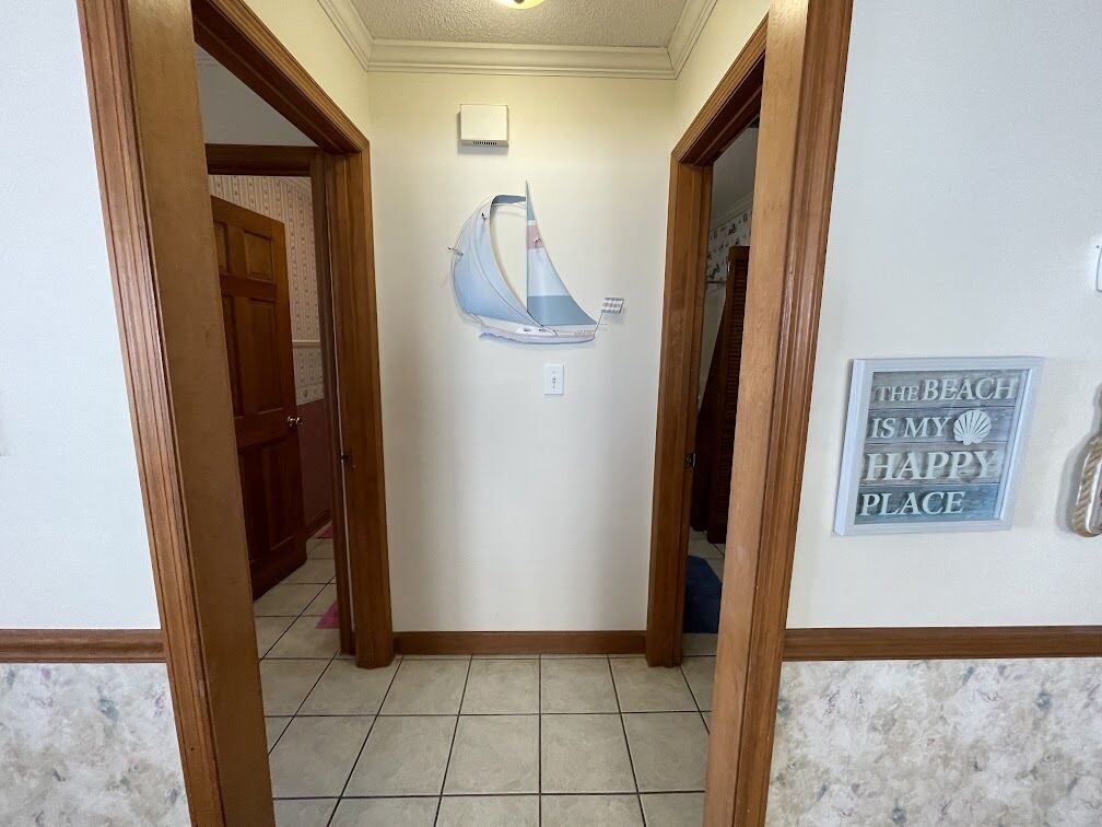 A hallway with a sailboat decoration, a sign saying "The Beach is my happy place," and a door leading to another room.