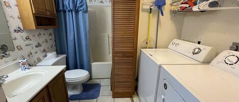 Een kleine badkamer met toilet, wastafel en wasmachine.