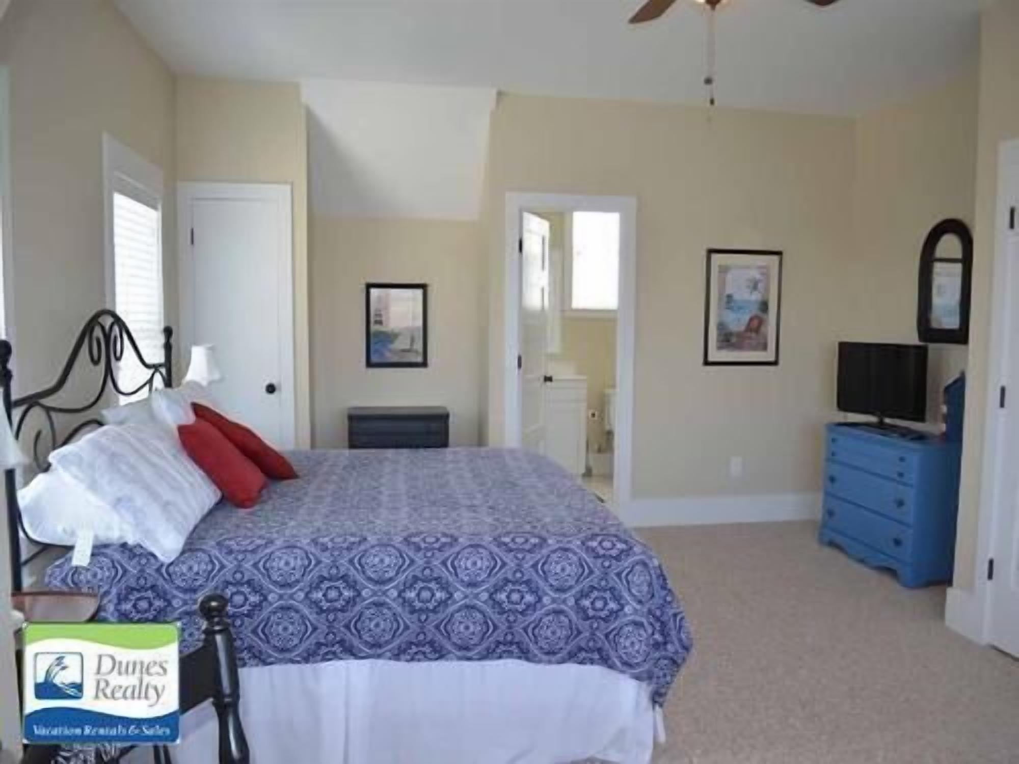 A bedroom with a bed, a dresser, and a ceiling fan.