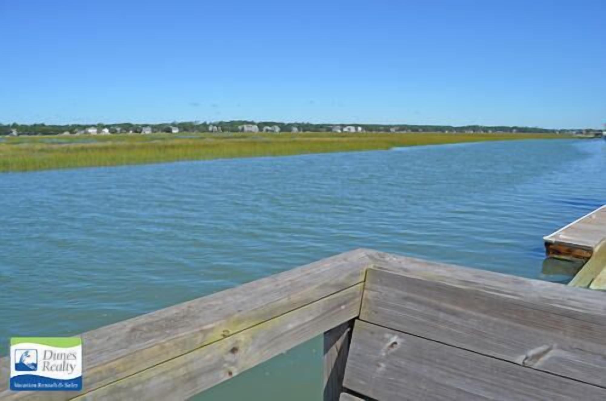 A wooden dock extending over calm water with a clear sky.