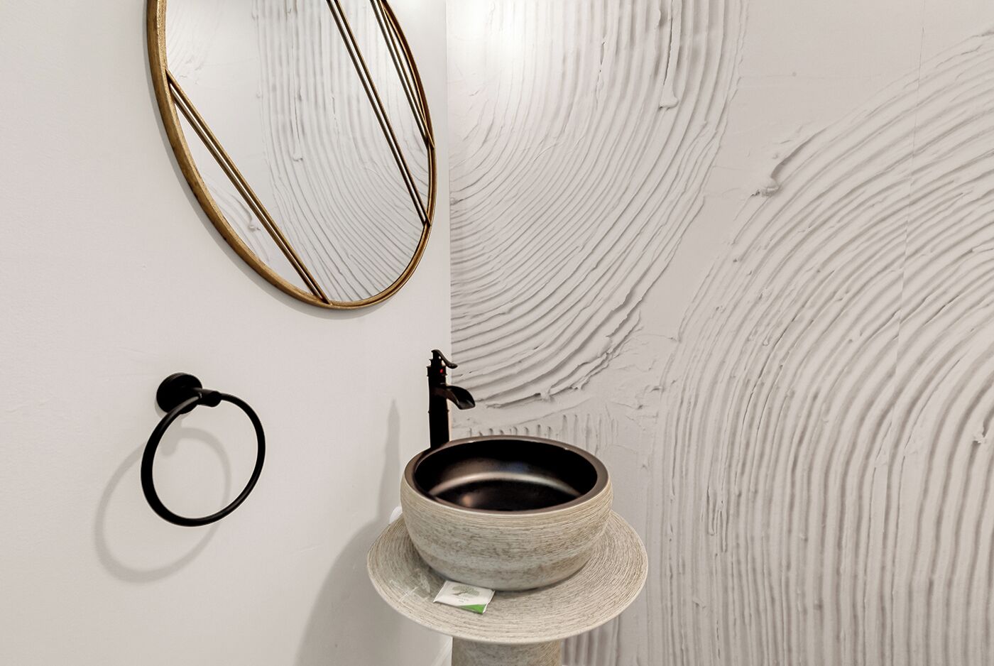 Une salle de bain avec un lavabo rond, un porte-serviettes et un miroir.