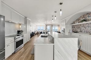 A modern kitchen with a central island, stainless steel appliances, and a view to the living area.