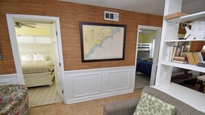Una habitación con cama, sofá, un mapa en la pared y una estantería.