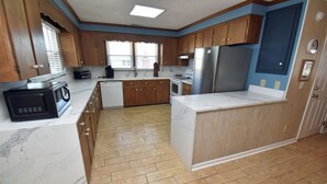 A kitchen with wooden cabinets, a microwave, a refrigerator, and a sink. - Electa's Place (Up) - Second Row in Garden City Beach (Garden City Beach)
