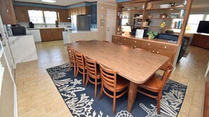 A compact kitchen with a dining area, wooden cabinets, a built-in microwave, and a large rug. - Electa's Place (Up) - Second Row in Garden City Beach (Garden City Beach)