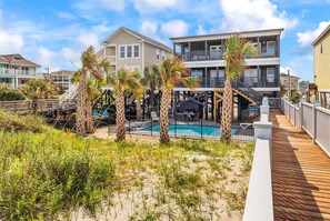 Ein Hotel direkt am Strand mit Pool, Palmen und einer Holzterrasse.