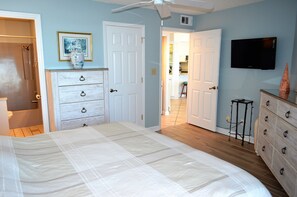 Une chambre à coucher avec un lit, une commode et un téléviseur.