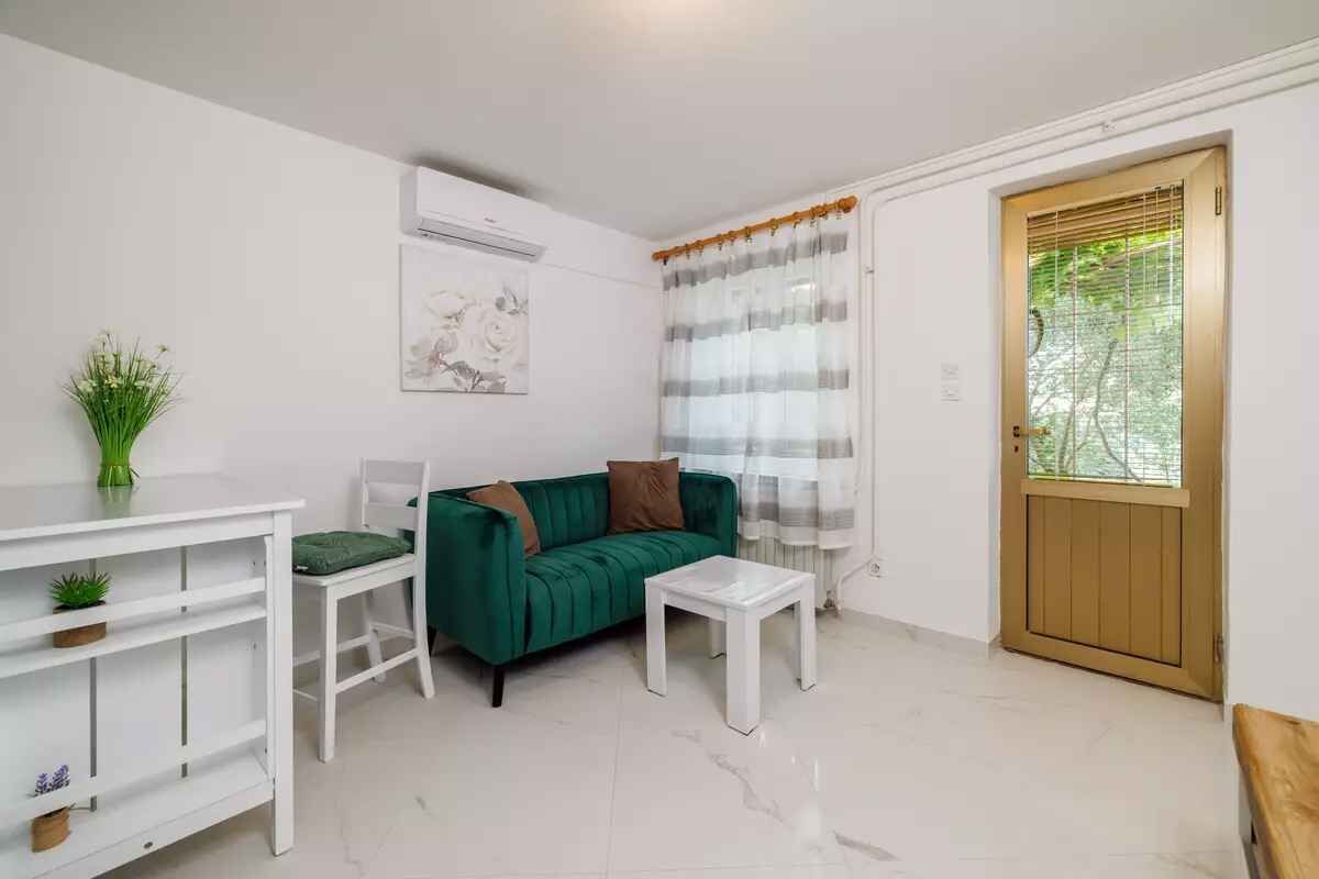 A living room with a green sofa, white coffee table, and a white TV stand.