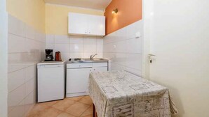 A compact kitchen with white cabinets, a coffee maker, and a sink. - Studio mit Terrasse und Klimaanlage (Jadranovo)