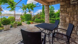 An outdoor patio with stone flooring, a table, and chairs. - Studio mit Terrasse und Klimaanlage (Jadranovo)