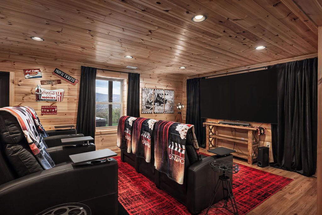 Una habitación acogedora con techo de madera, un televisor de pantalla plana grande, un área de estar cómoda con alfombra roja y un ventanal con vistas panorámicas.
