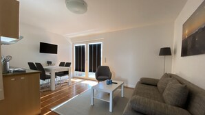 Een moderne woonkamer met een bank, een salontafel en een eethoek met stoelen en een tafel.