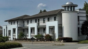 Een modern gebouw met een centraal torentje en meerdere balkons.