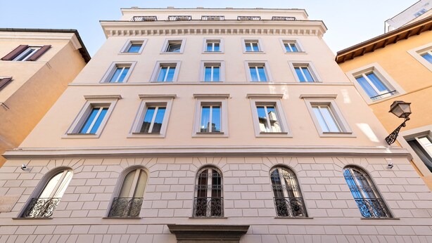 Un immeuble à plusieurs étages doté d’une façade symétrique, de grandes fenêtres et d’une porte verte.