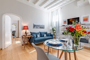 Ein modernes Wohnzimmer mit einem blauen Sofa, einem Glastisch und einem Stadtbild an der Wand.