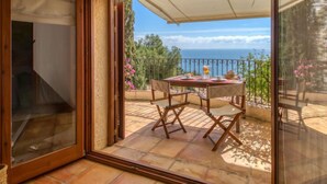 Ein Zimmer mit einer Schiebetür, die auf eine Außenpatio mit einem Tisch für zwei Personen führt, mit Blick auf die malerische Seelandschaft.