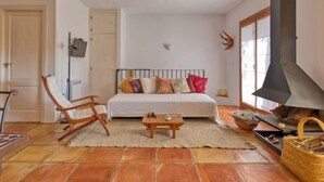Ein gemütliches Schlafzimmer mit Bett, Schaukelstuhl, einem kleinen Tisch, Kamin und Fenster mit Blick.