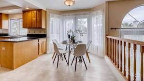 Una cocina moderna con armarios de madera, encimera negra y un comedor con mesa redonda y cuatro sillas.