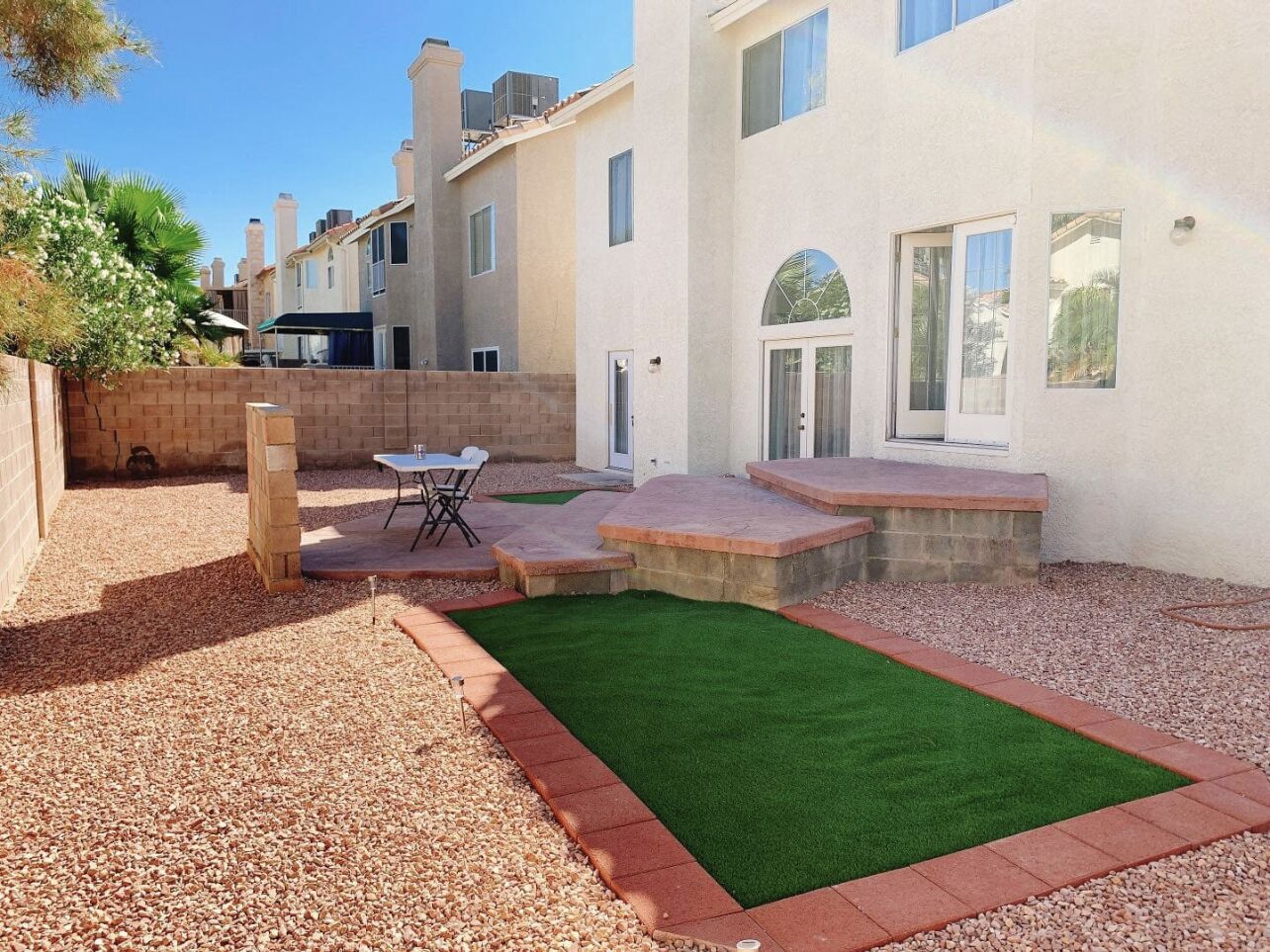 A residential property with a patio, artificial grass, and a brick wall.