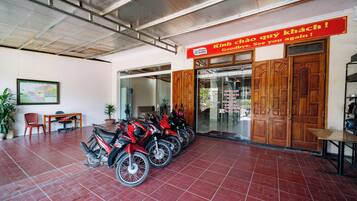 A motorcycle rental shop with a red sign, wooden doors, and several red motorcycles parked inside.