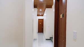 A hallway with a wooden ceiling, white walls, and a tiled floor. - HG Hostel and Motobikes (Ha Giang 1)
