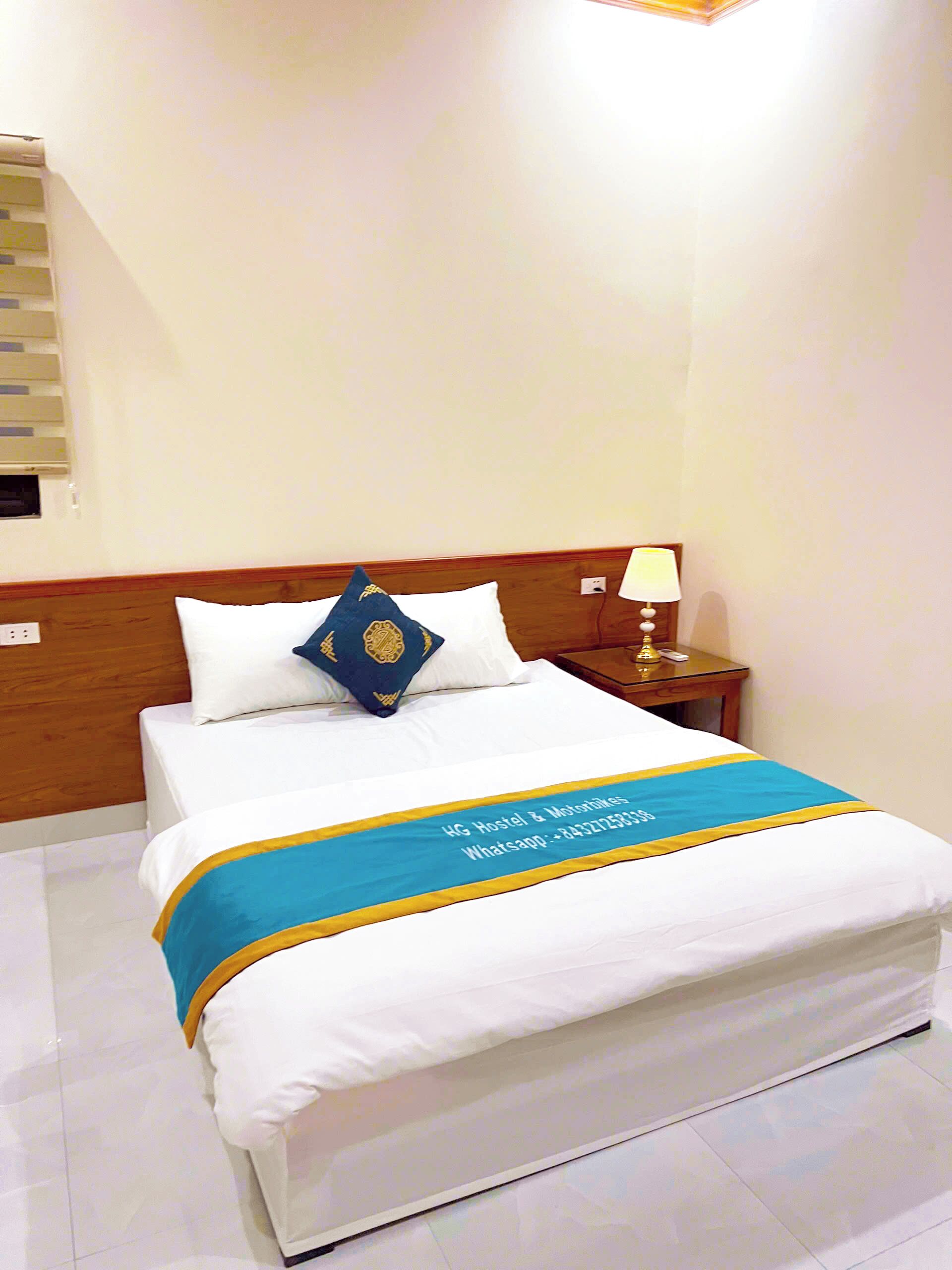 A neatly made bed with a blue and yellow bedspread, white pillows, and a wooden headboard.