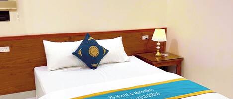 A neatly made bed with a blue and yellow bedspread, white pillows, and a wooden headboard.