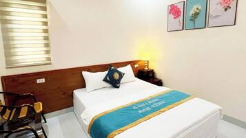 Una habitación de hotel con una cama, una mesita de noche, una lámpara, una silla y tres cuadros en la pared.