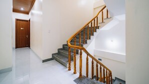 A staircase with wooden balusters and granite steps, leading to a landing with a wooden door. - HG Hostel and Motobikes (Ha Giang 1)