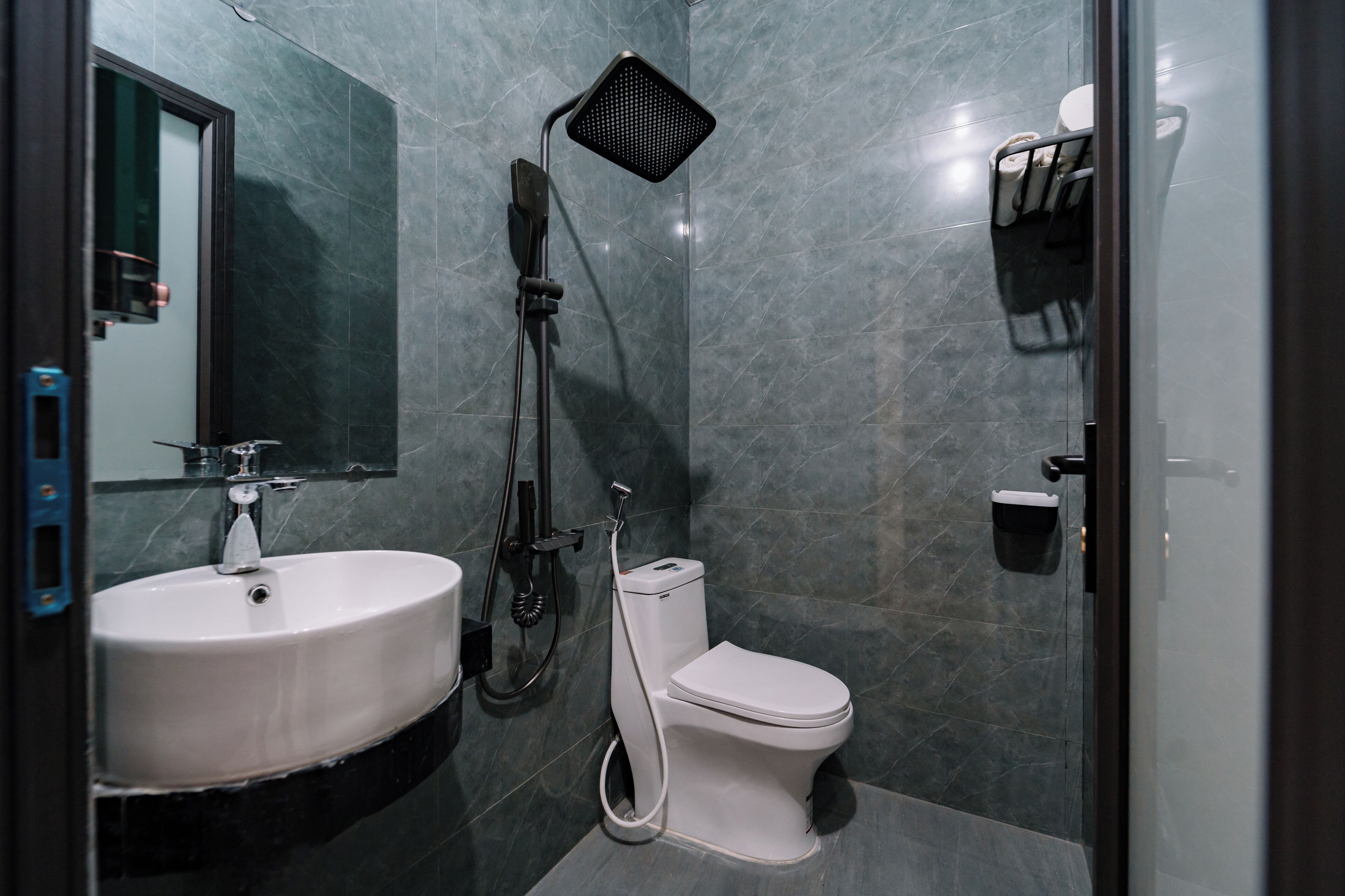 Un baño moderno con un lavamanos blanco, inodoro y ducha con cabezal de ducha manual.