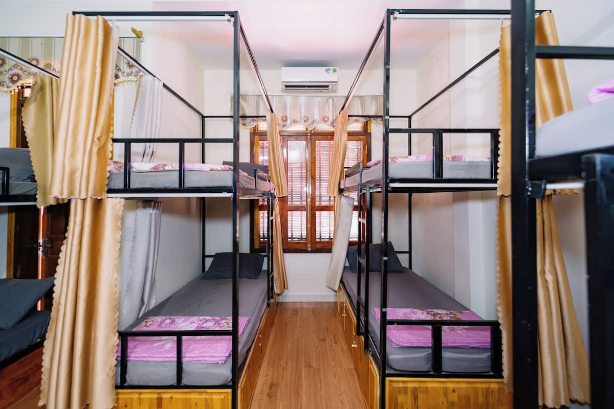 A bunk room with two beds, wooden flooring, and curtains.