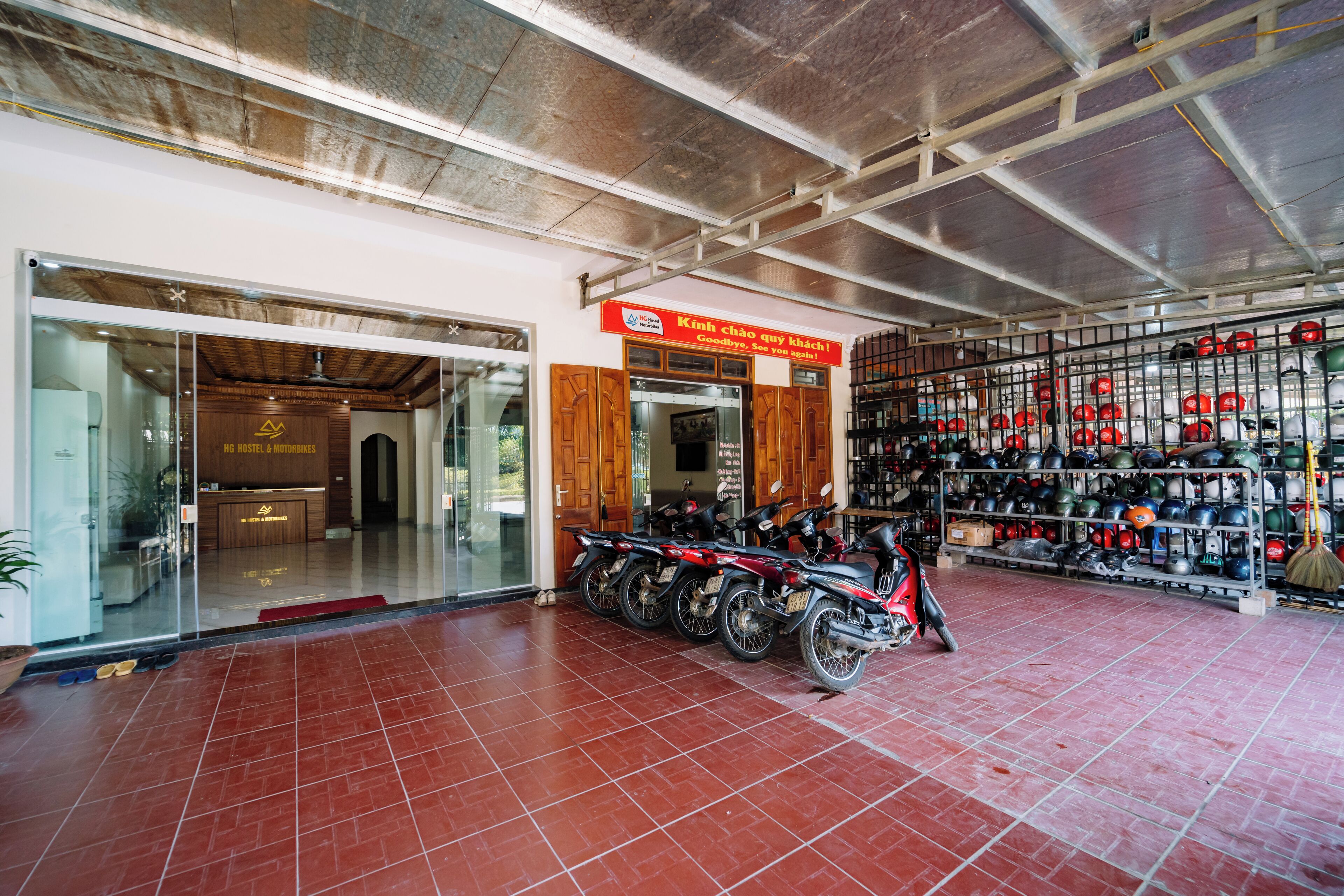 A motorcycle rental shop with a red sign, a glass door entrance, and a wall of helmets and helmets.