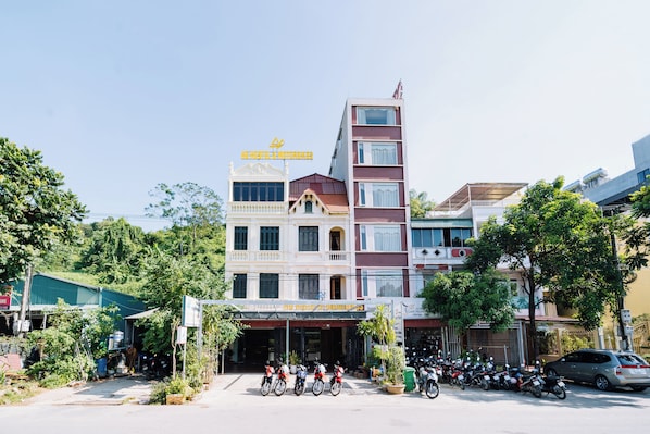 Edifício de vários andares com entrada central, cercado por motocicletas estacionadas e alguns carros.