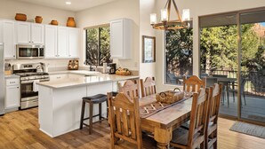 A spacious kitchen with white cabinets, a large island, and a dining area with wooden chairs. - Luxury Sedona Living: Remodeled w/ Red Rock Views! (Sedona)