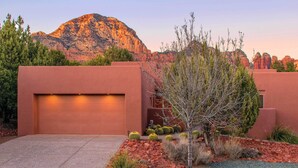 A modern building with a garage, surrounded by a landscaped garden with cacti and a small tree. - Luxury Sedona Living: Remodeled w/ Red Rock Views! (Sedona)