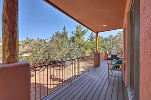 A wooden deck with a metal railing, a green chair, and a barbecue grill. - Luxury Sedona Living: Remodeled w/ Red Rock Views! (Sedona)