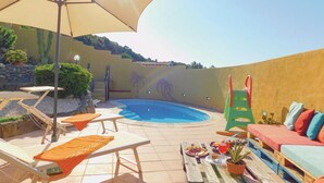 A backyard with a swimming pool, lounge chairs, a table with food, and a colorful play structure. - Amazing apartment in Gonnesa (Gonnesa)