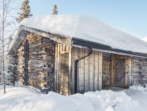 A log cabin with a wooden door and a snow-covered roof.